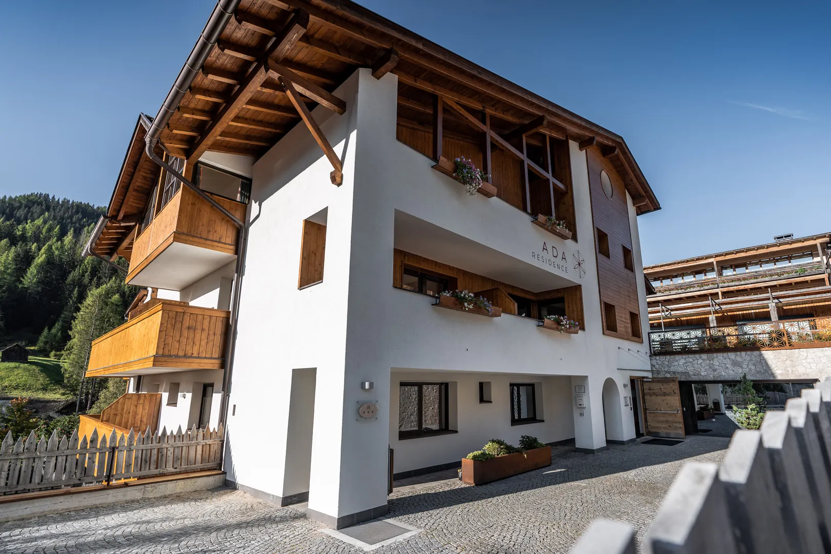 Residence Ada - facciata con balconi in legno e vista sul paese