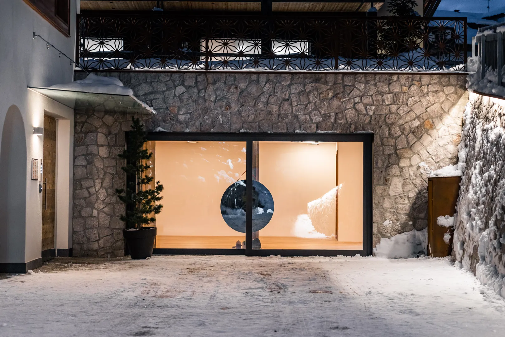 Residence Ada - ingresso con parete in pietra e portale vetrato in inverno