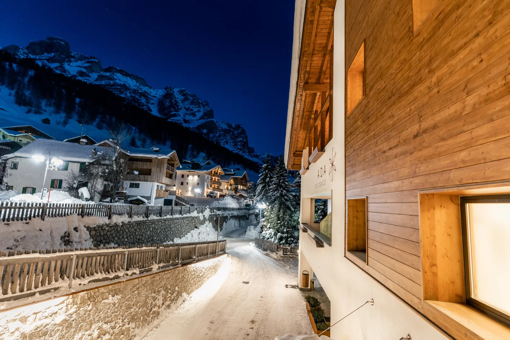 Residence Ada al tramonto d'inverno, finestre illuminate e strada innevata