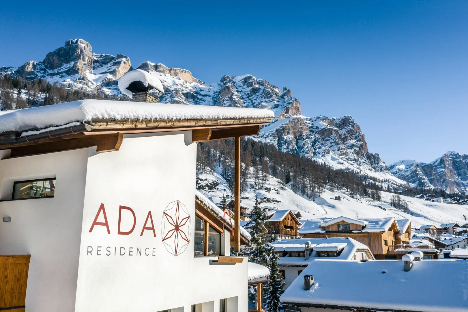 Residence Ada - logo sulla facciata con le cime innevate delle Dolomiti sullo sfondo