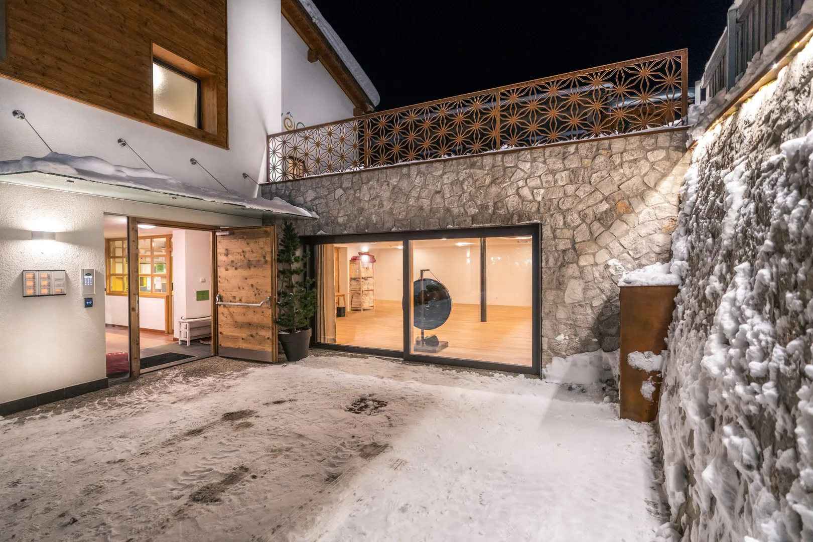Residence Ada - ingresso illuminato con parete in pietra in una sera d'inverno