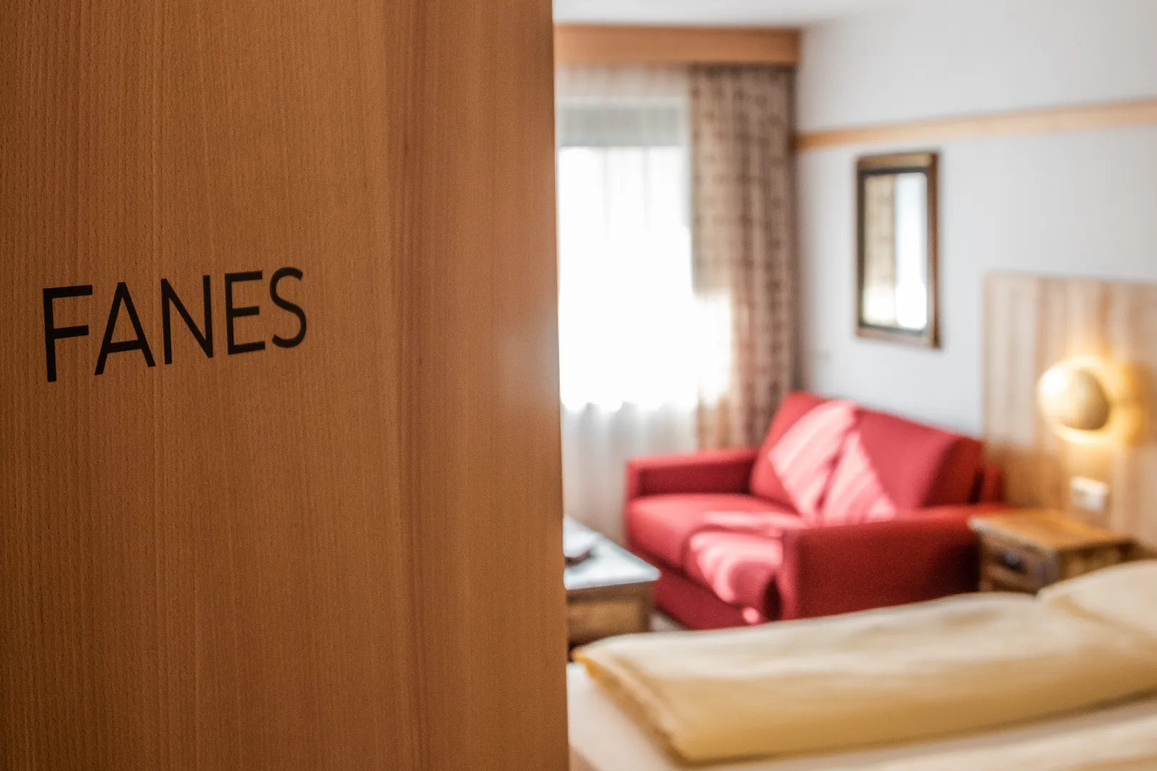 Residence Ada - camera Fanes con divano rosso e porta in legno